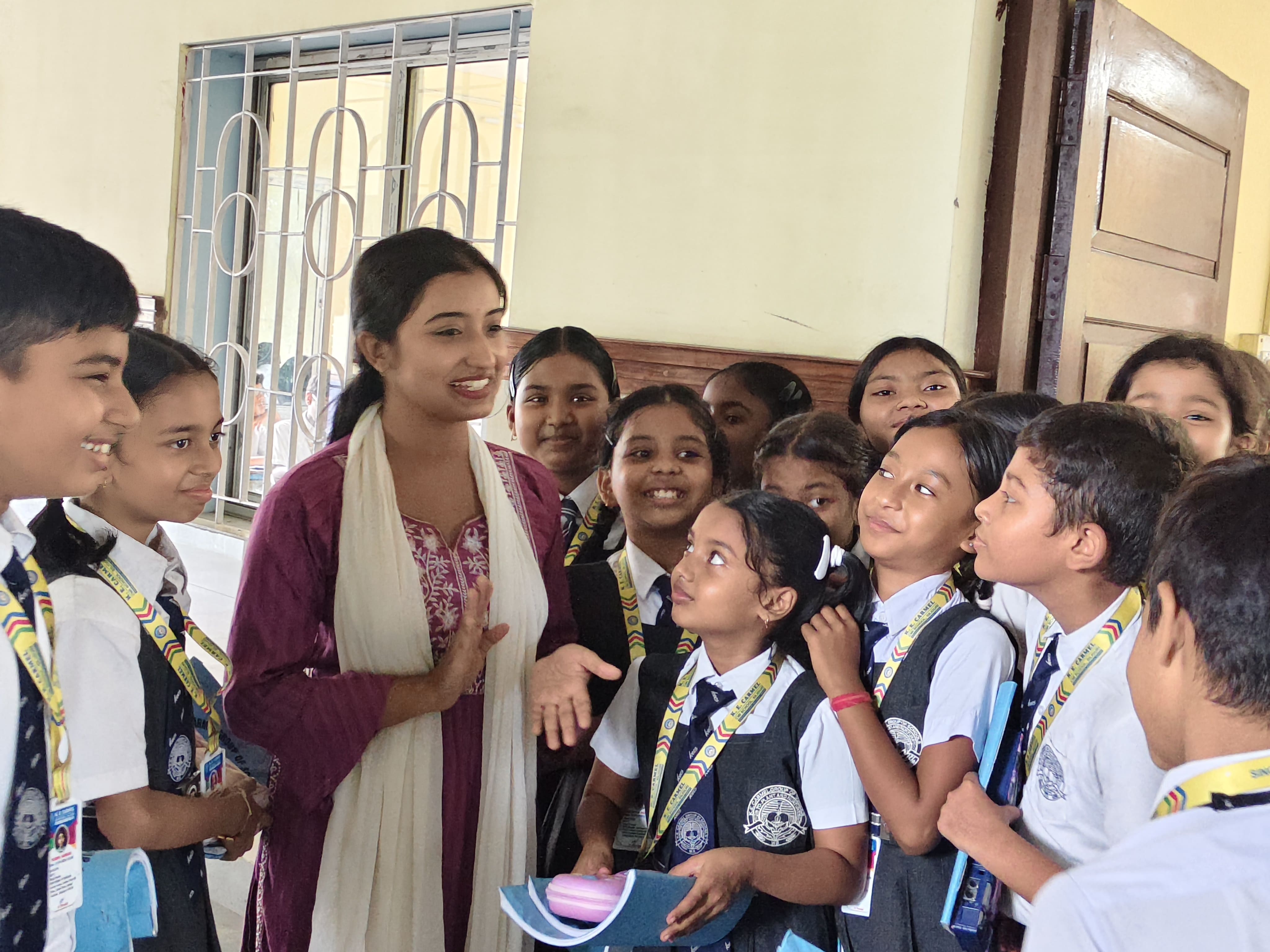 Students standing in a corridor with teachers in the background